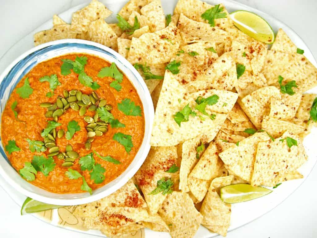 Overhead shot of bowl of red pepper and peptita salsa with chips.