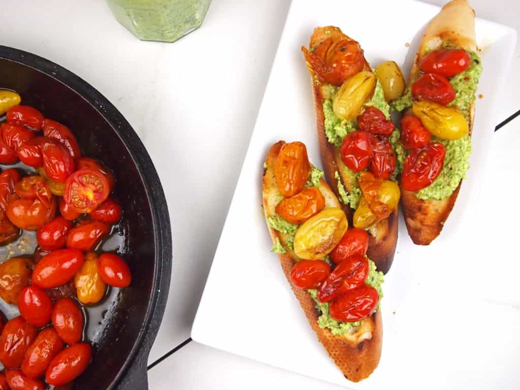 Roasted tomatoes in a cast iron skillet with bruschetta on the side. 
