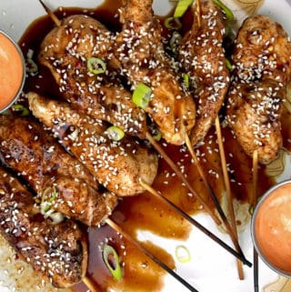 Chicken skewers on a platter with honey hoisin sauce and sriracha mayo for dipping