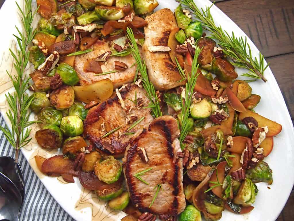 A platter of cider braised pork on a bed of caramelized brussels sprouts