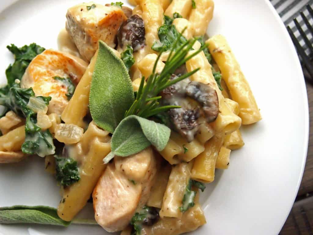 Chicken, mushroom, and kale pasta bake with sage and rosemary on a plate