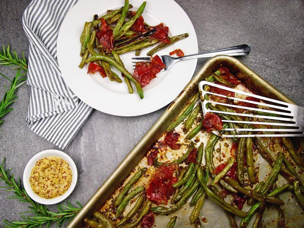 overview of a plate and sheet pan of crispy green beans, prosciutto, and mustard vinaigrette 