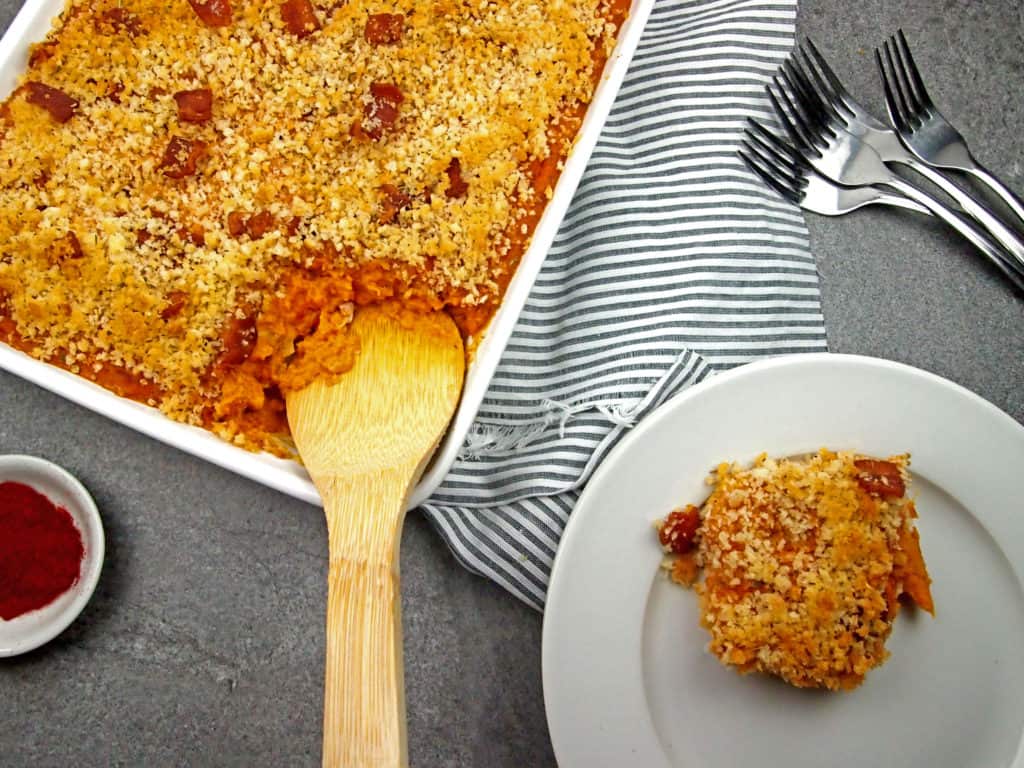 A serving of savory sweet potato casserole being spooned out on a dish