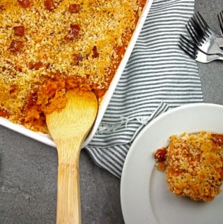 A serving of savory sweet potato casserole being spooned out on a dish