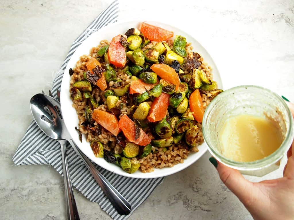 Drizzling of citrus vinaigrette on farro salad with brussels sprouts