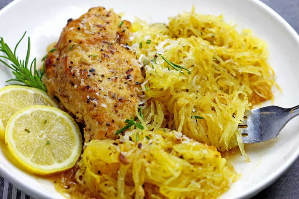 A plate of braised lemon chicken with spaghetti squash with a fork