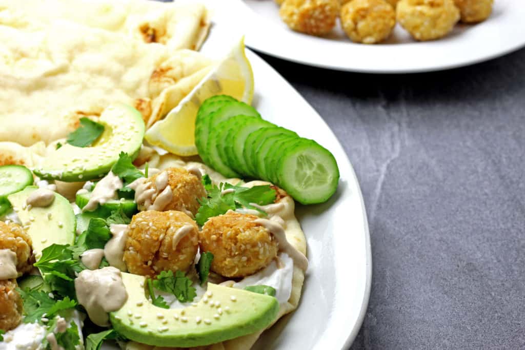 Sesame falafel with tahini drizzle on a gray background