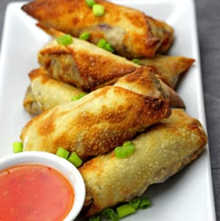 Egg rolls on a plate with dipping sauce on the side