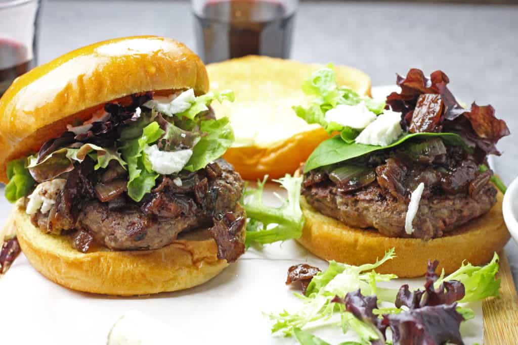 Burgers with onion, red wine, and bacon jam with spring mix and goat cheese