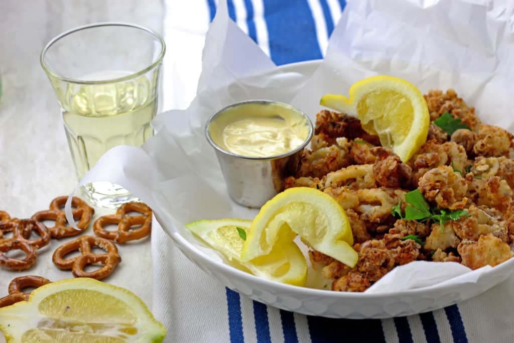 Crunchy air fryer calamari in a bowl with lemons, parsley, and mustard dipping sauce served with white wine on the side.