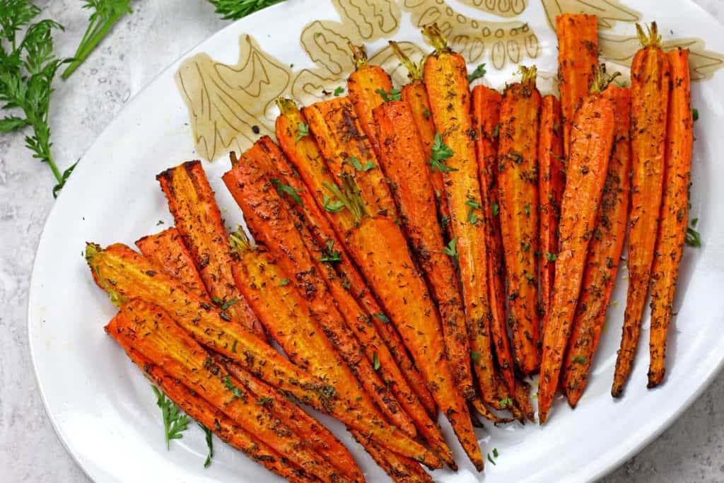 Caramelized air fryer carrots on a plate topped with dill and parmesan