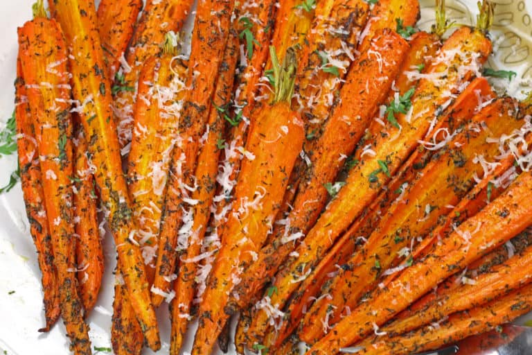 A plate of roasted carrots garnished with herbs and grated cheese. The carrots are cooked to a golden brown, sprinkled with seasoning, and topped with a light layer of cheese for added texture and flavor.
