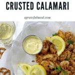 Overhead view of crunchy air fryer calamari in a bowl with lemons, parsley, and mustard dipping sauce served with white wine on the side with text overlay saying "Air Fryer Pretzel Crusted Calamari"