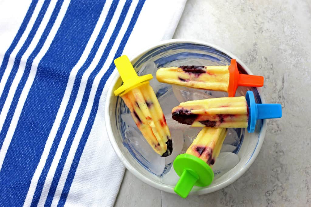Cherry Mango Popsicles laid out in a bowl of ice.