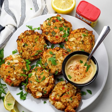 Overview of air fryer crab cakes with a sauce on a white background