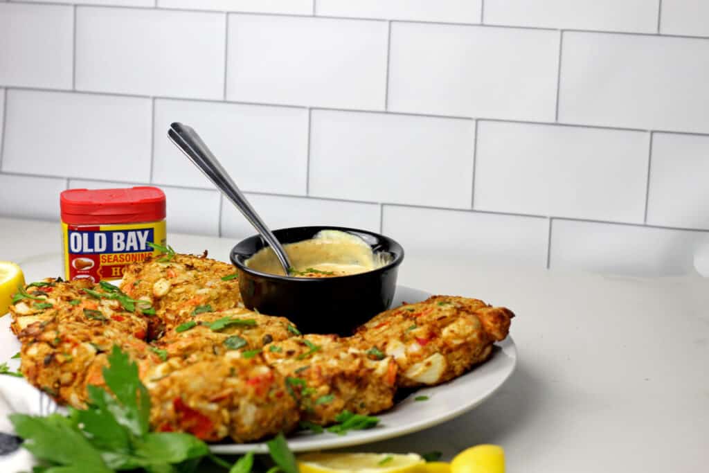 Air fryer crab cakes with a sauce on platter with a subway tile background