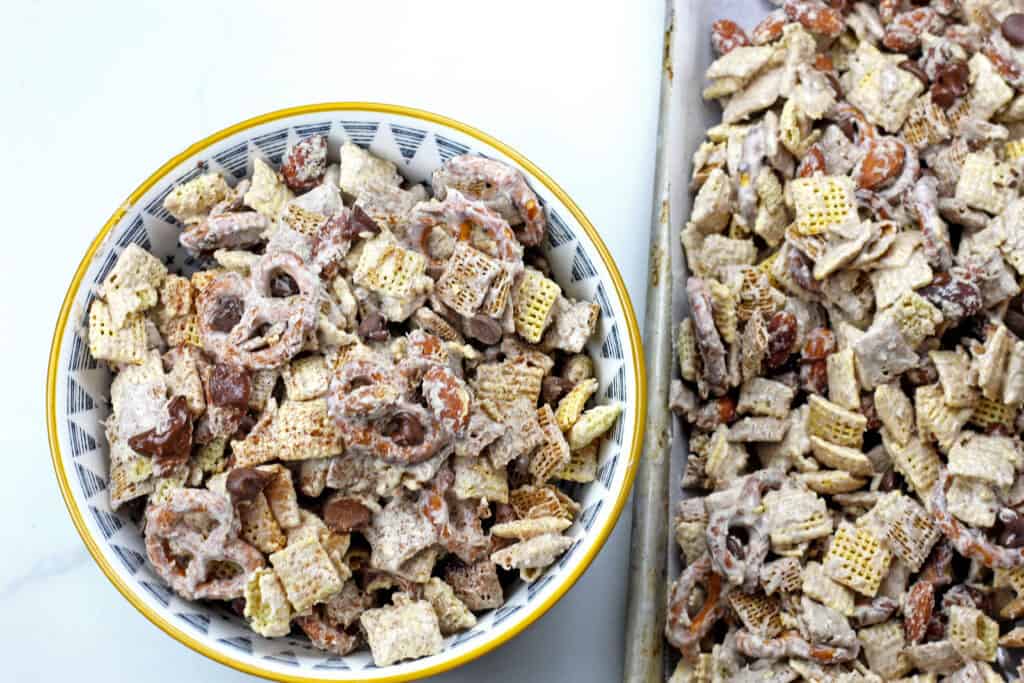 Bowl of churro chex mix next to a sheet pan of churro chex mix