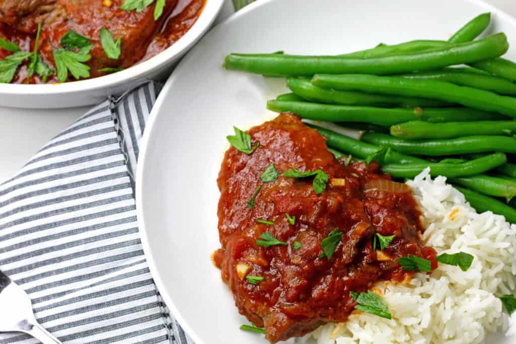 A plate of instant pot swiss steak with green beans and rice.