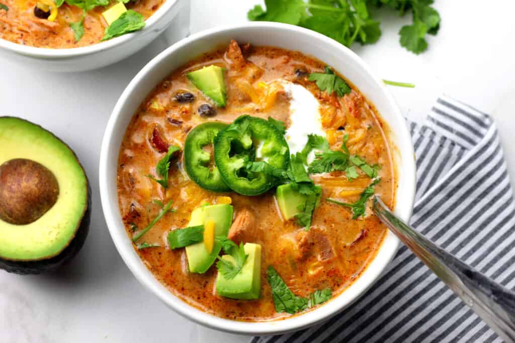 Overview of creamy enchilada soup with a spoon in the bowl on a white countertop