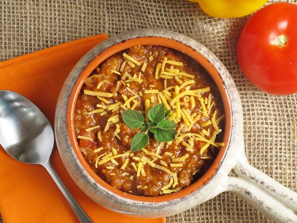Ground turkey slow cooker recipe with a turkey, lentil, and white bean chili on a burlap background with an orange napkin and spoon.
