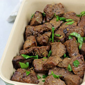 Close-up of air fryer steak bites with parsley garnished on top.