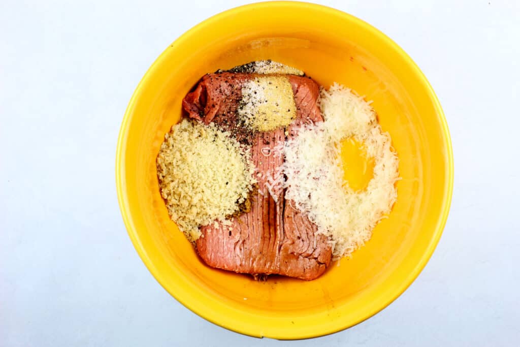 Ingredients for air fryer turkey meatballs in a yellow bowl on a white background.