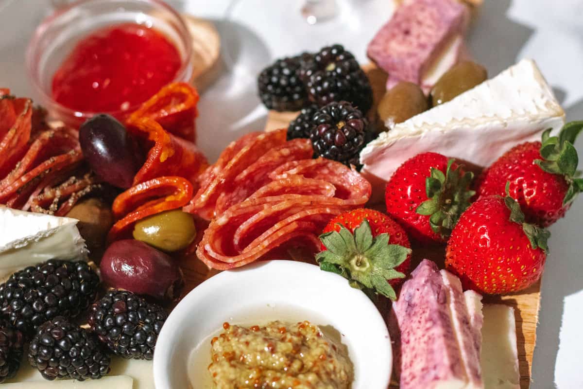 Close up of mini charcuterie boards loaded with cheee, meat, mustard, and jelly.