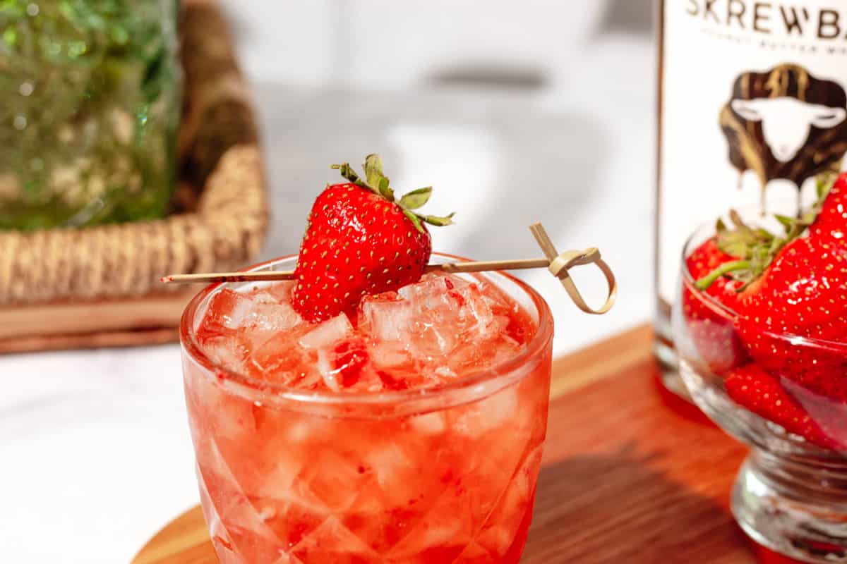 Close up of a peanut butter and jelly cocktail with a strawberry skewered for garnish.