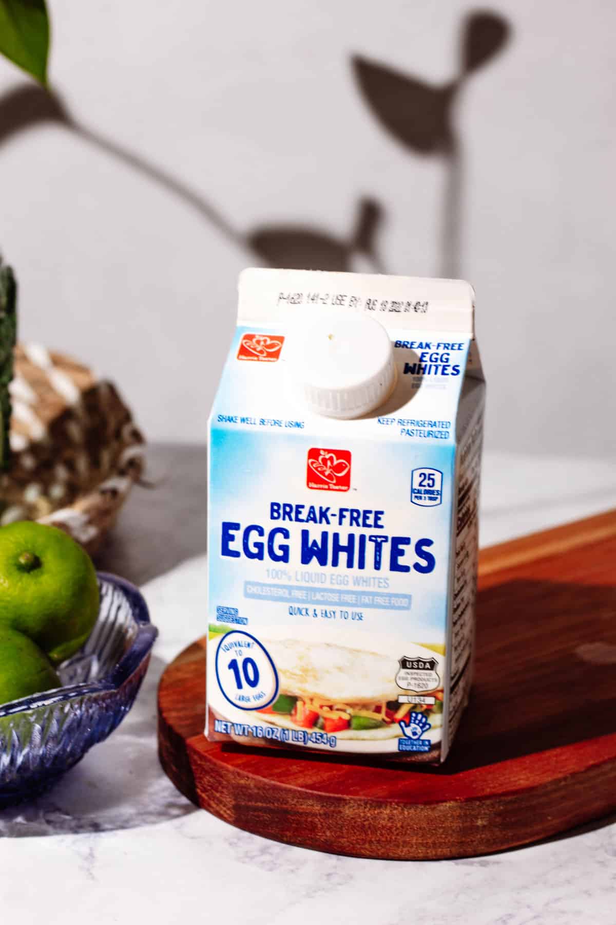 A carton of egg whites sitting on a wood cutting board