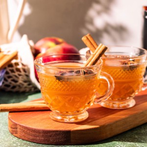 Two glasses of hot toddy on a wood cutting board.