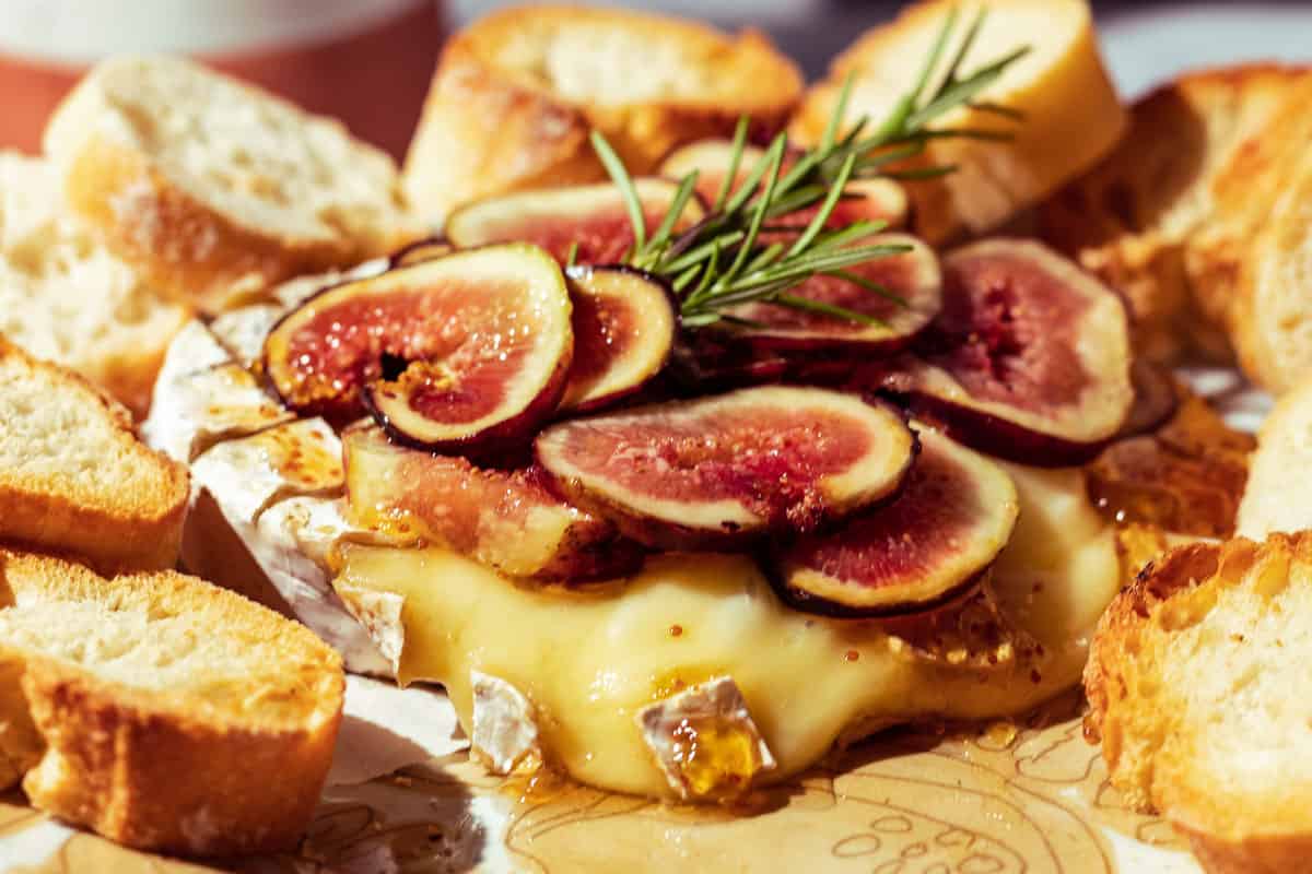 Melted brie cheese with fresh figs and bread slices.