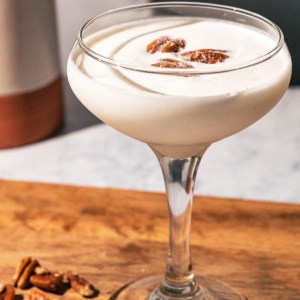 Pecan martini on a wood cutting board with pecans scattered.