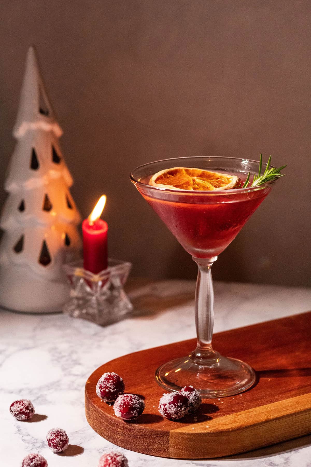 Mistletoe martini sitting on a wood cutting board with sugared cranberries on the side.