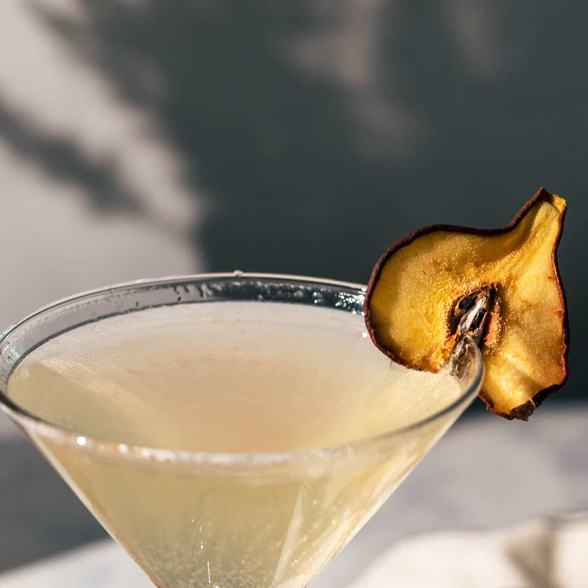 Pear cocktail in a martini glass with a dried pear garnish.