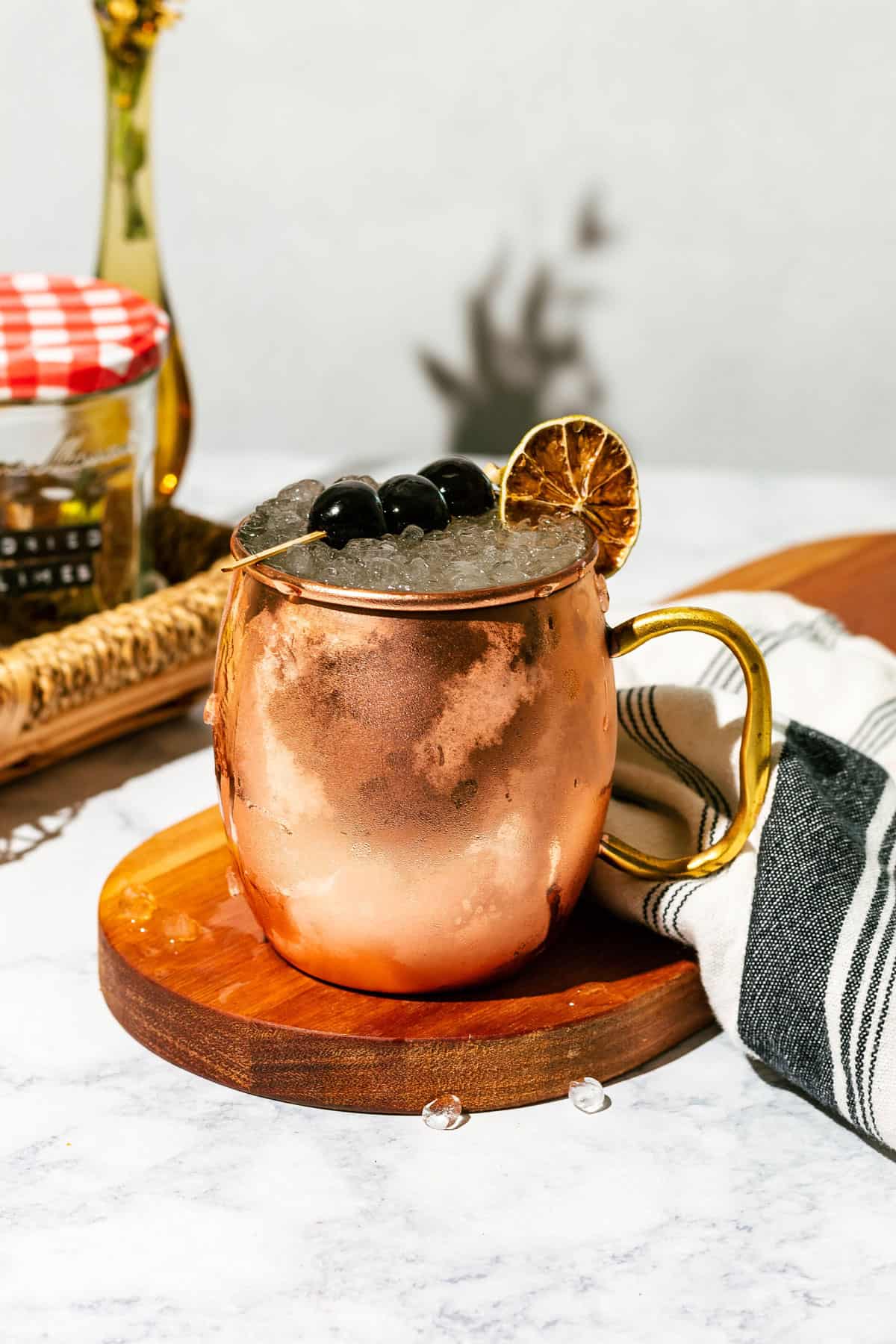 Cocktail copper mug on a wood cutting board on a white marble counter.