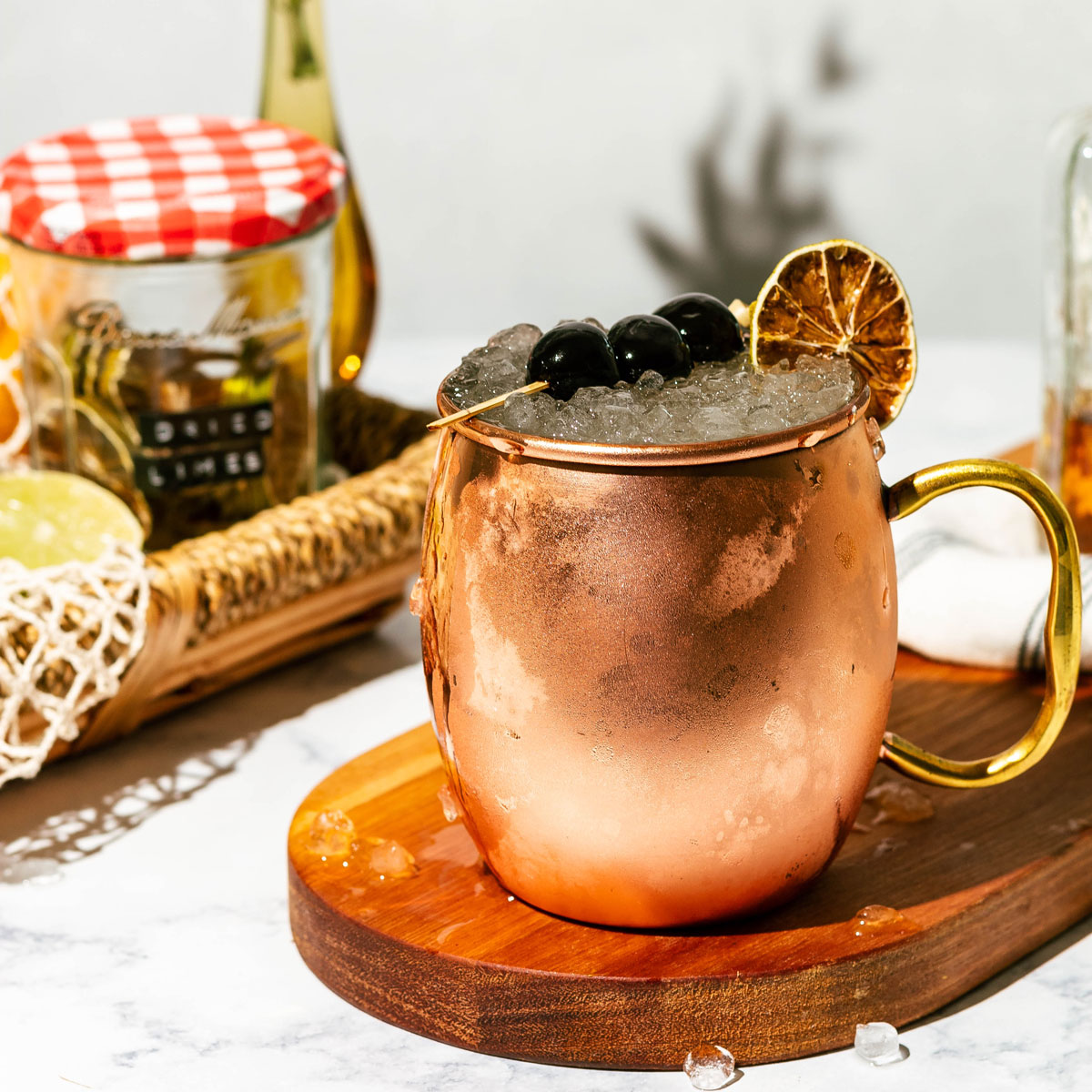 Italian mule in a copper mug with ice spilling out onto a wood board and marble counter.