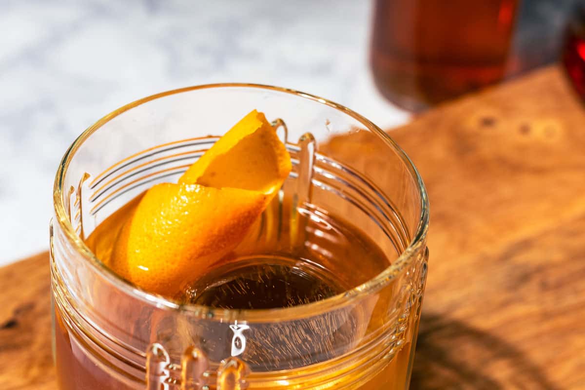 Rum old fashioned with a orange twist on a wood cutting board.