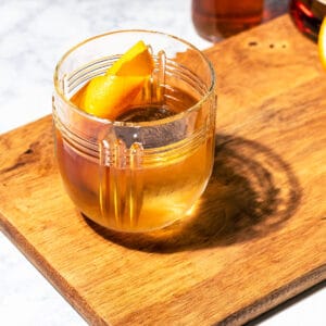 Rum old fashioned with light shining through on a wood board.