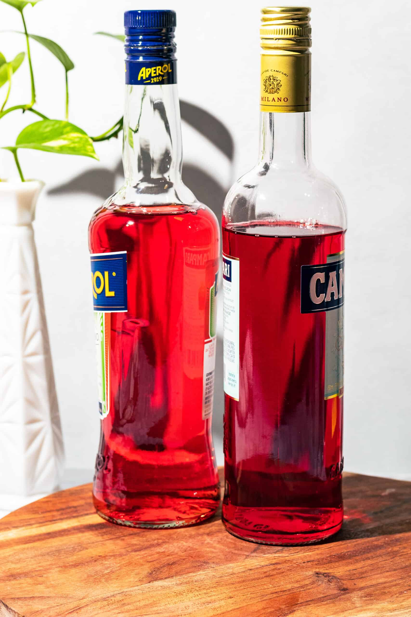 Aperol and Campari bottles side by side showing the orange vs. red color of the two aperitifs. 