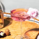 Pink spritz in a coupe glass with fluffy cotton candy on the rim.