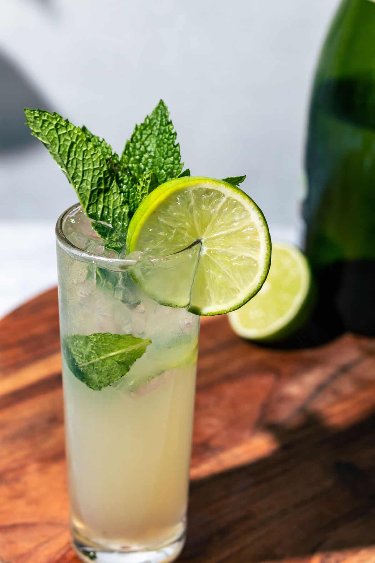 Mojito Royale in a tall highball glass on a wood cutting board.