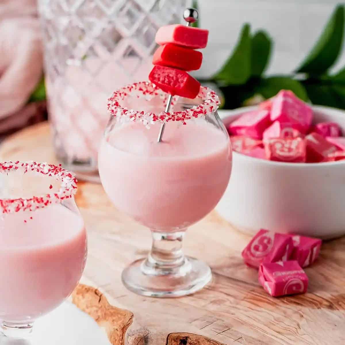 Pink cocktail in a small glass garnished with starburst candy.