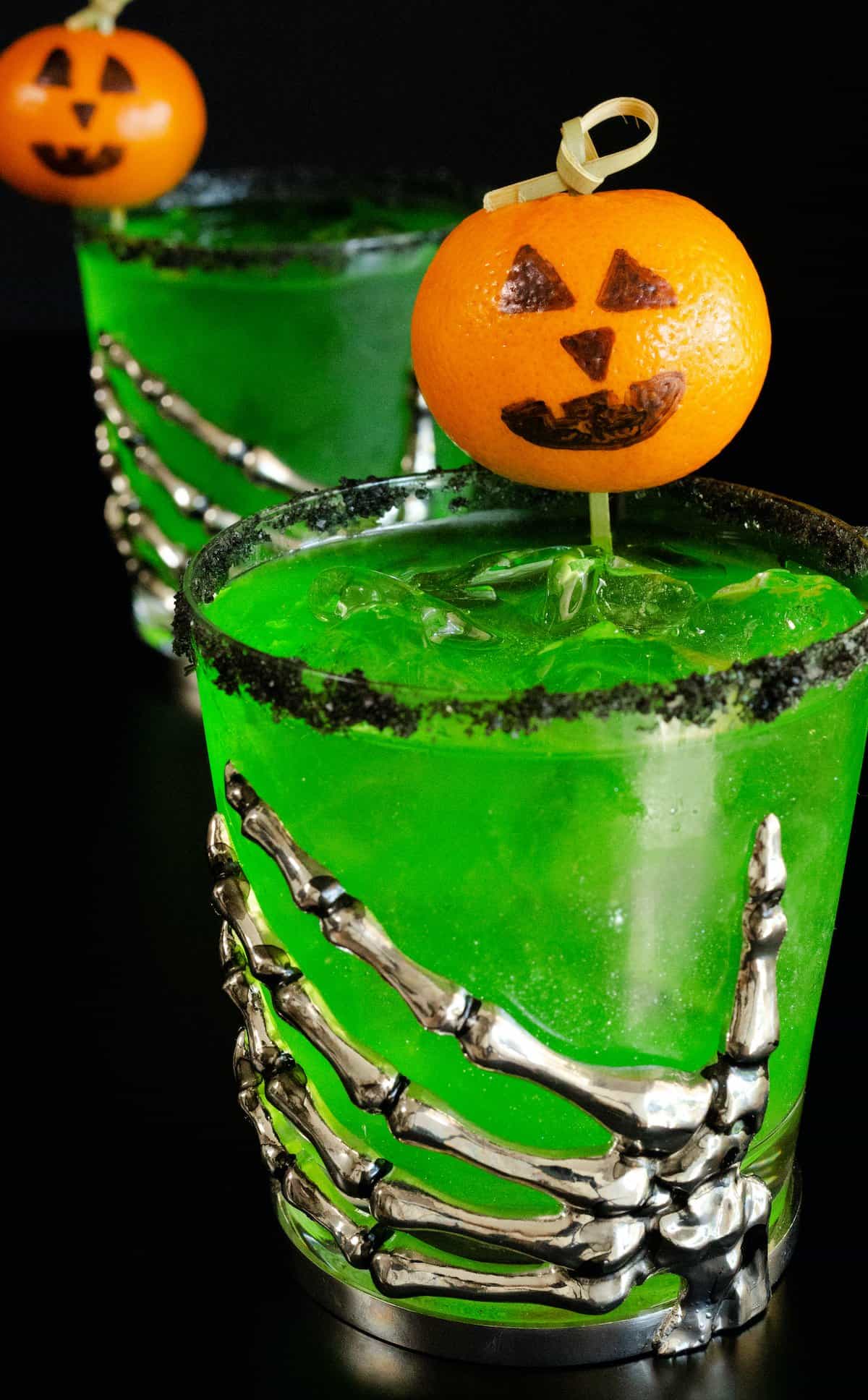 Green Halloween Margarita garnished with a jack-o-lantern cocktail pick.