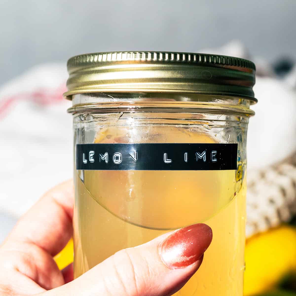 Someone holding the jar of syrup that is labeled with words "lemon lime".