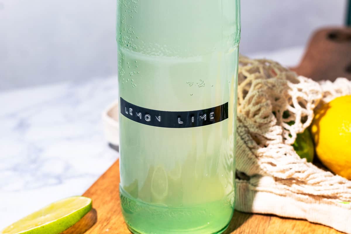 Bottle with a label that says "lemon lime" on a wood surface.