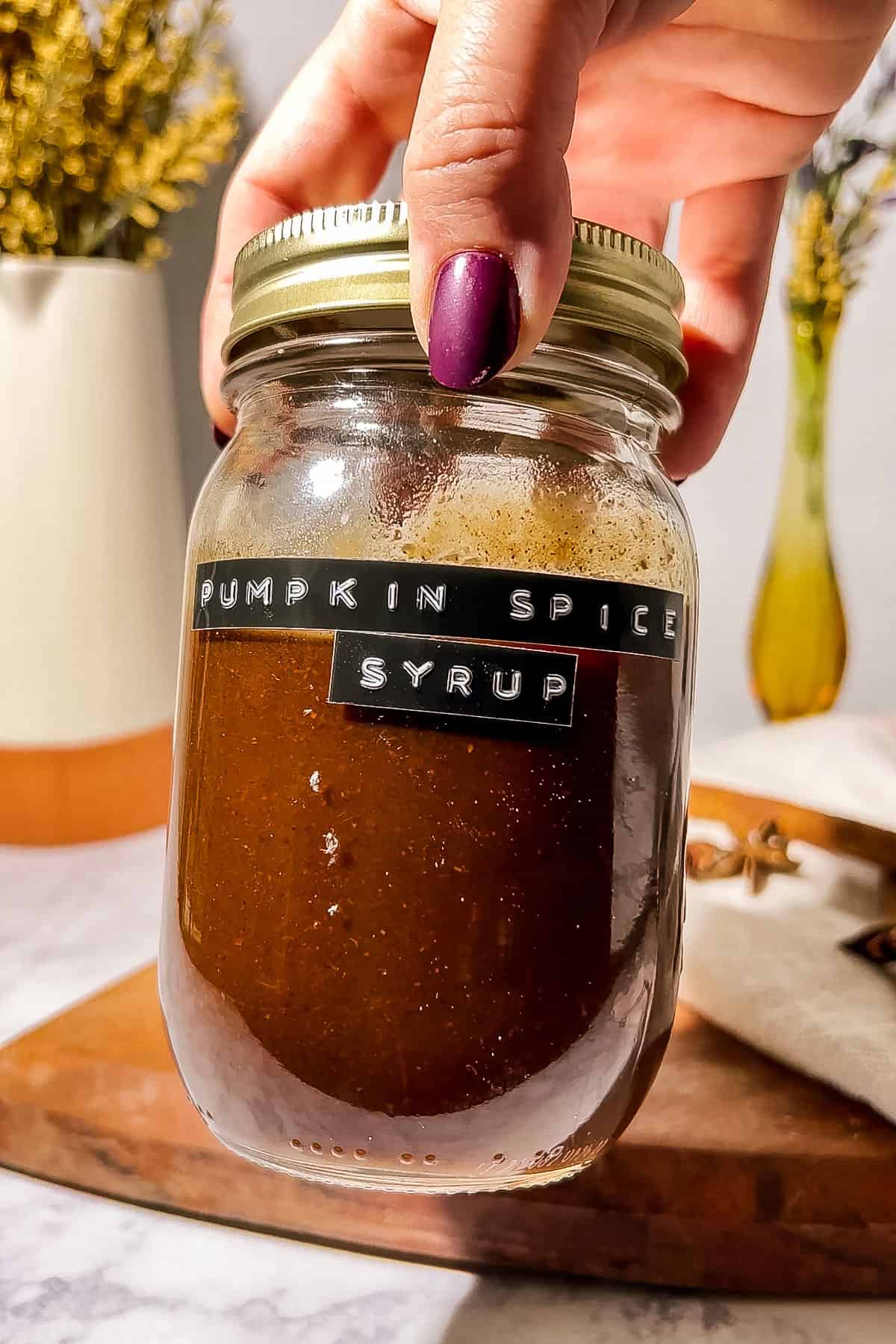 Someone holding the jar of syrup in their hand.