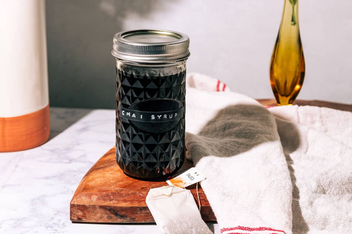 Bottle of the syrup on a wood surface with a kitchen towel.