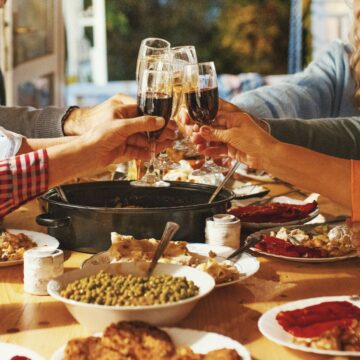 People clinking glasses over a thanksgiving table.