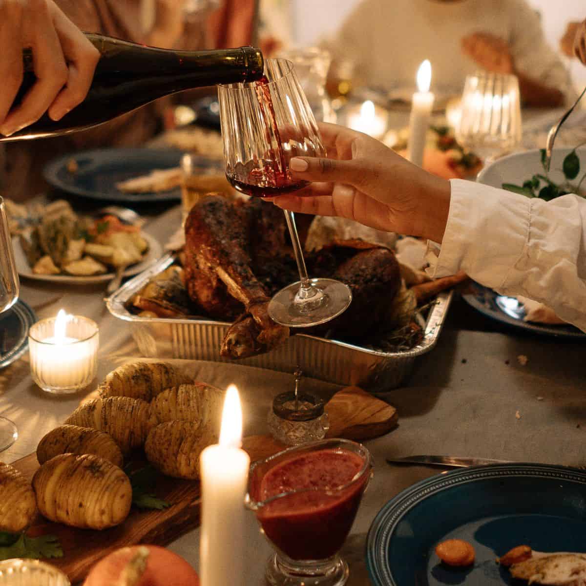 Someone pouring wine across a thanksgiving table.