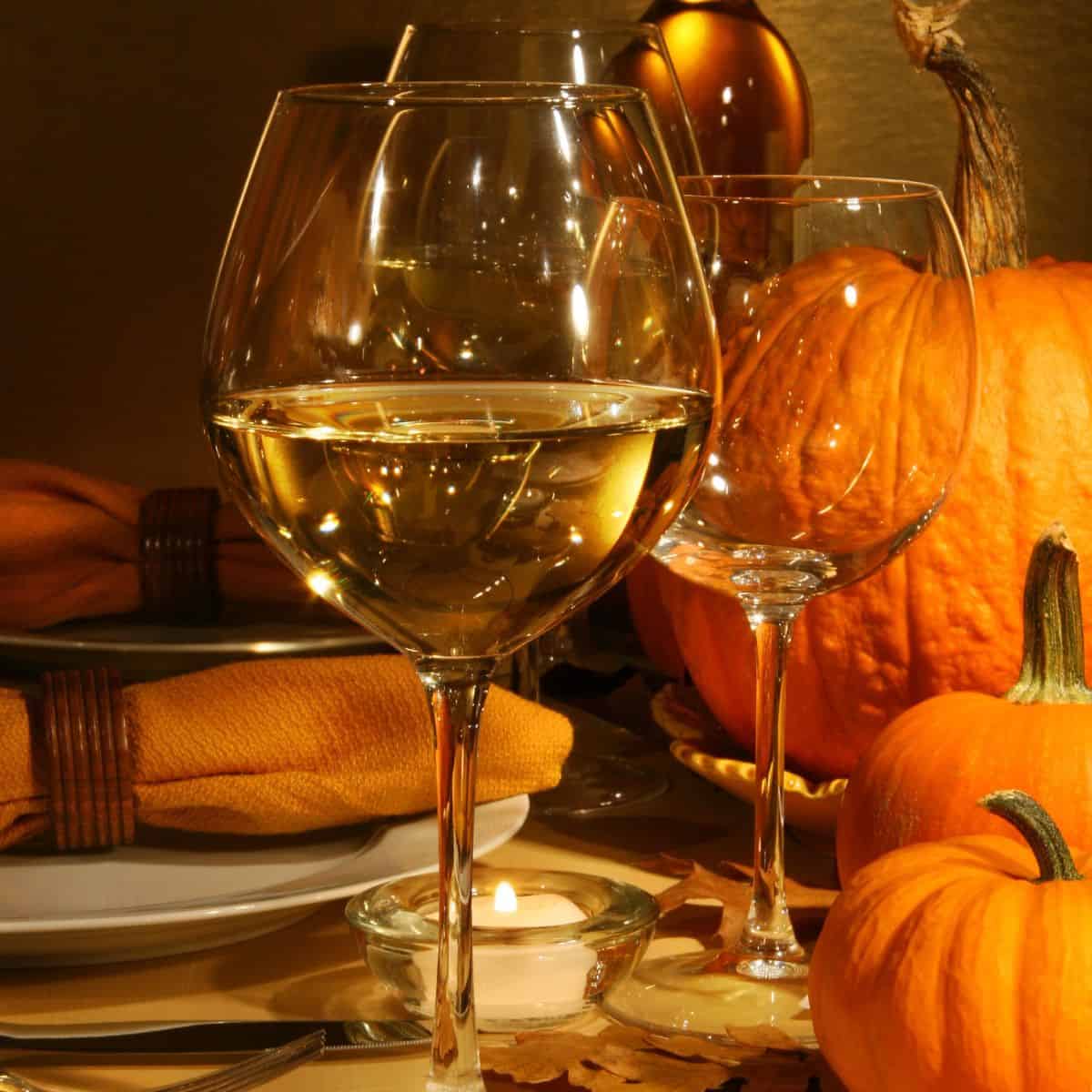 Glasses of white wine with pumpkins in the background.